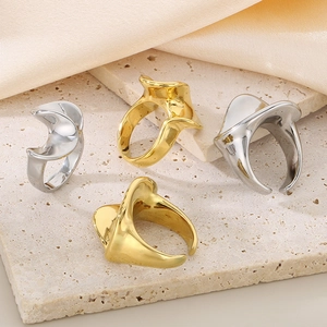 Abstract wave-shaped 18K gold and silver plated stainless steel rings on stone base