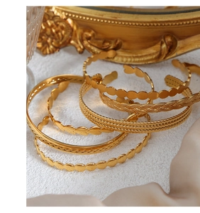 Detailed view of textured gold bracelets with wave and rope patterns on satin base