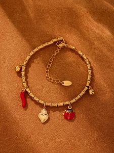 Detaillierte Nahaufnahme des goldenen Bambus-Armbands mit roten Emaille-Anhängern