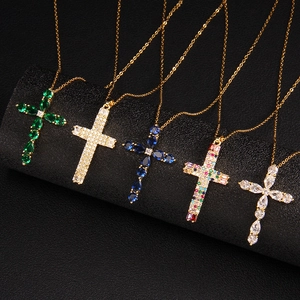 Golden cross necklaces set with colorful zirconia crystals on a black jewelry stand