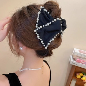 Détail d'une grande pince à cheveux nœud satin noir avec bordures élégantes en perles
