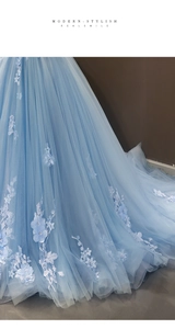 Detailed embroidery and 3D floral patches on light blue tulle of a bridal ball gown
