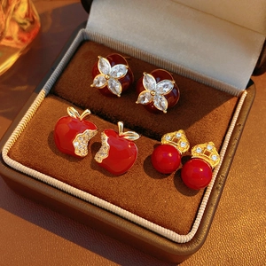 Macro shot of three pairs of red floral and apple stud earrings in a luxury jewelry box