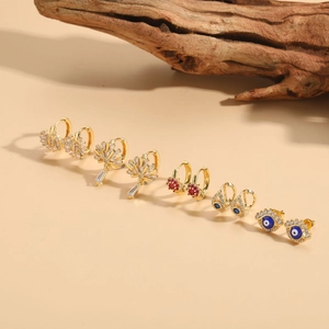 Detailed collection of five golden zircon earrings with evil eye and floral motifs