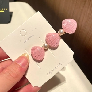 Close-up of pink glitter shell hair clip with pearls on a branded Korean display card