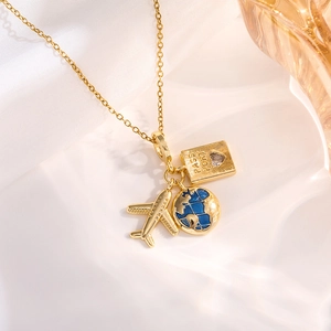 Macro shot of gold travel necklace with airplane, globe, and heart passport pendants