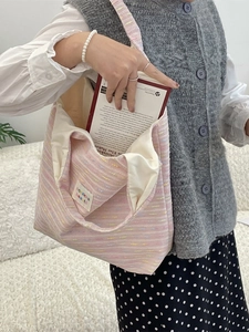 Pink striped fabric tote bag with embroidery shown on a model in a minimalist setting