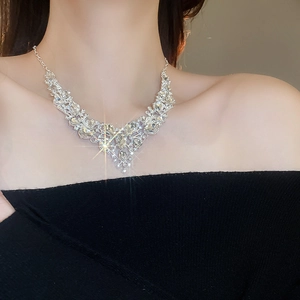 Macro shot of silver V-shaped rhinestone drop necklace on model with sparkling detail