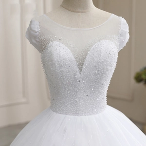 Détail d'une robe de mariée blanche avec des paillettes faites main et des manches bouffantes