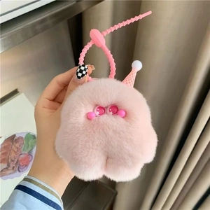 Pink plush monster keychain with silicone strap held in hand for size detail