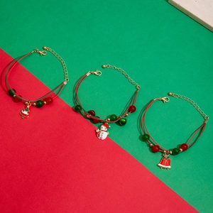 Detail of red and green Christmas bracelets with snowman and bell charms on stone