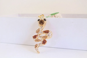 Detailed close-up of golden snake pendant with sparkling amber and clear rhinestones