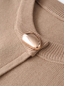 Detail of coffee knit fabric texture and irregular light gold metal button closure