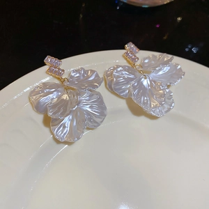 Detail of shell petal earrings with zirconia accents on white porcelain tray