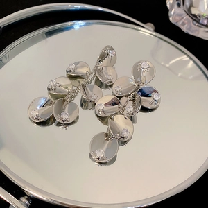 Detailed view of silver flower tassel earrings with crystals on a reflective mirror