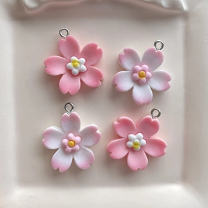 Macro view of four pink and white cherry blossom resin pendants with metal rings