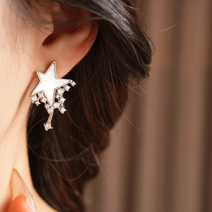 Close-up of silver star earrings with mother-of-pearl inlay and zircon tassels on model