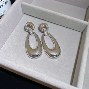 Close-up of silver hollow oval earrings with micro-paved zircons in a jewelry box