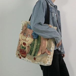 Detail of jacquard tote bag featuring artistic cartoon cat and cherry print pattern