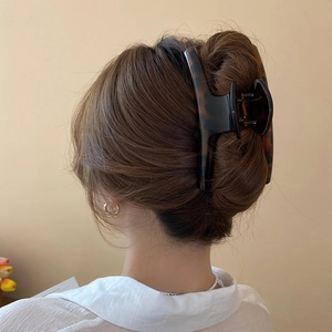 Detail of large tortoiseshell leopard print hair claw clip in a back-of-head hairstyle