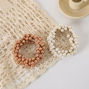 Close-up of pearl elastic hair scrunchies in champagne and white on lace fabric