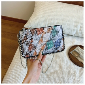 Detail of snakeskin patchwork envelope bag with metallic bead trim and chain strap