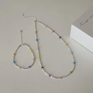 Close-up of colorful crystal and silver bead necklace set on a soft gray surface