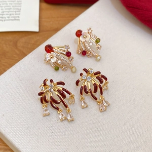 Macro detail of firework gold earrings with red enamel and dangling crystal teardrops
