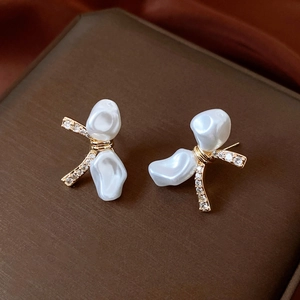 Detail of 18k gold plated bow earrings with baroque pearls and sparkling zircon accents