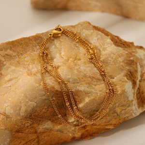 Detailed view of triple-layer 18K gold-plated beaded chain bracelet with lobster clasp