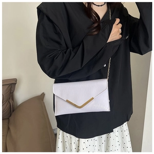 Détail du sac enveloppe blanc plissé avec logo V doré et bandoulière en chaîne