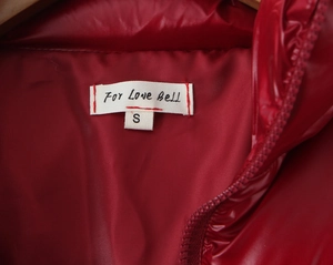 Detail of red puffer jacket collar showing brand tag For Love Bell and size S label