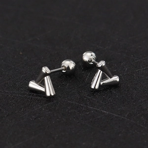 Macro view of geometric triangle screw-back studs in polished surgical stainless steel