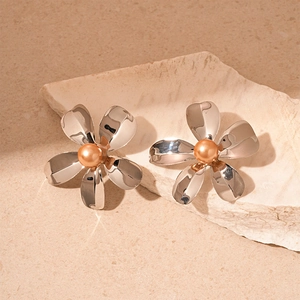 Detail of silver petal flower earrings with champagne pearl on a beige stone