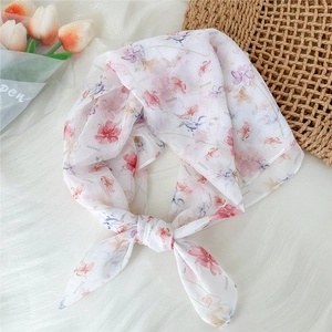 Detail of knotted sheer floral silk scarf with pink flower print and brand pattern