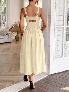 Detail of the backless design and wide straps on the light yellow pleated midi dress