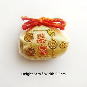 Macro detail of embroidered lucky pouch brooch with golden fabric and Daji character