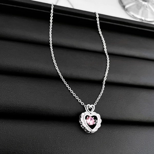 Detailed close-up of a silver heart pendant featuring a round pink zircon center stone