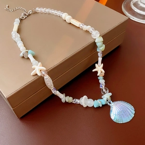 Detailed view of starfish and iridescent shell pendant on a beaded necklace strand