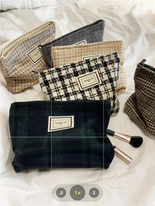 Assorted plaid tweed makeup bags with textured patterns on white fabric background