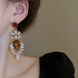 Close-up of vintage teardrop earrings with amber and iridescent crystals on a model