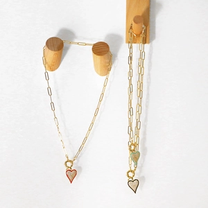 Détail de pendentifs cœur en émail et cristaux sur une chaîne trombone dorée chic