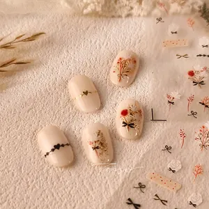 Macro detail of floral and bow nail stickers with gold stamping on cream press-on nails