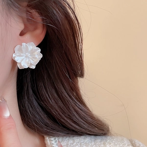 Macro view of multi-layered white pearl flower stud earrings worn on elegant model
