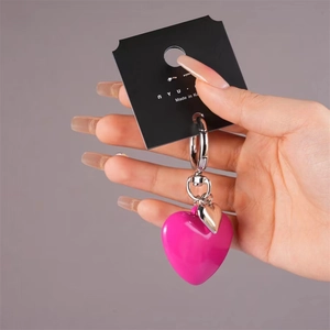 Handheld large rose pink resin heart keychain with silver metal ring on gray background
