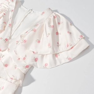 Détail des manches à volants et de l'imprimé roses roses sur une robe blanc cassé