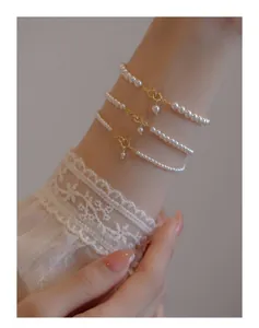 Close-up of three layered white pearl bracelets with golden ring clasps on a wrist