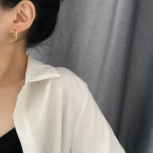 Elegant multi-layer geometric hoop earrings in polished gold finish on female model