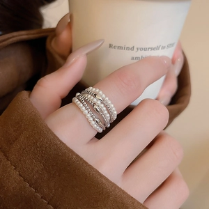Close-up of multilayer pearl and metal bead ring worn while holding a coffee cup