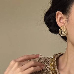 Detailed close-up of vintage gold hollow textured oval earrings on model